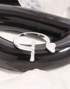 Macro shot of silver sterling open ring with cross and heart elements on black stand