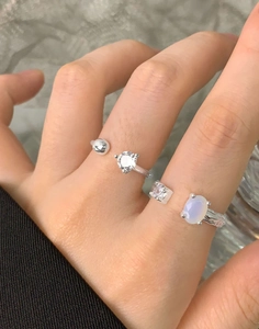 Detail of S925 sterling silver open rings featuring round zircon and opal on model hand