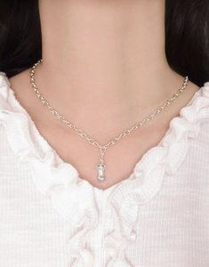 Silver apple core pendant on O-chain shown on a model with white knitwear