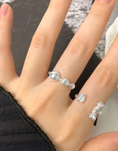 Close-up of S925 silver liquid heart rings set on hand with molten metal design