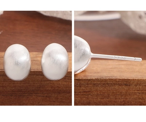 Détail de boucles d'oreilles ovales en argent S925 mat avec texture brossée et poinçon