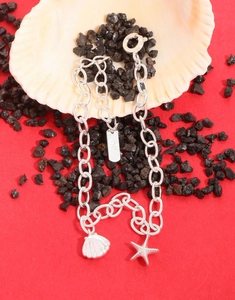 Detailed macro view of S925 sterling silver shell and starfish charms on a link chain bracelet