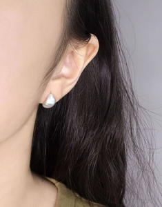 Boucle d'oreille en argent poli forme haricot montrant un éclat métallique sur l'oreille