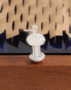 Macro shot of silver mushroom-shaped pendant with high-polish finish on wood