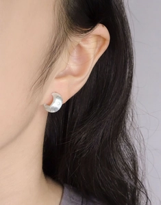 Close-up of S925 sterling silver crescent stud earrings with brushed matte texture