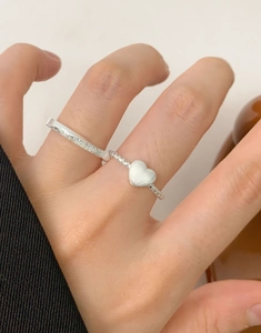 Detail of S925 sterling silver Mobius rings featuring frosted texture and a heart charm