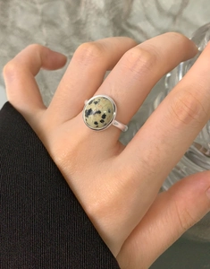 Macro shot of S925 sterling silver ring with round natural spotted stone on finger