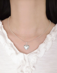 Detailed view of S925 sterling silver heart pendant with bow engraving on neck