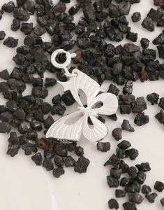 Macro shot of S925 sterling silver butterfly pendant with brushed texture on black stones
