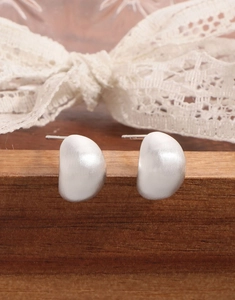 Gros plan de boucles d'oreilles mates en argent S925 montrant le poinçon S925 gravé