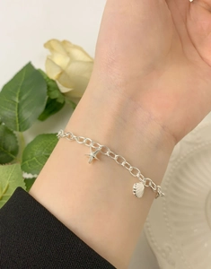 Detail of S925 sterling silver chain bracelet with starfish and seashell charms