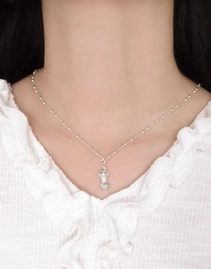 Macro shot of silver apple core pendant on ball chain against white lace collar