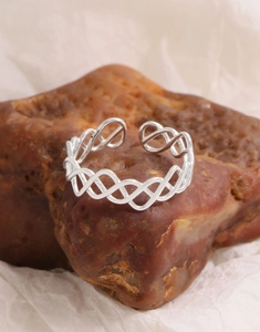 Gros plan d'une bague ouverte tressée en argent avec motif ondulé sur pierre brune
