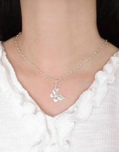 Detailed view of an S925 sterling silver butterfly pendant worn on a beaded chain necklace