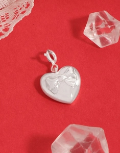 Detailed view of S925 sterling silver heart pendant with embossed bow on red background