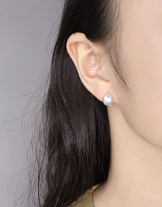 Vue rapprochée de boucles d'oreilles minimalistes en argent mat en forme de haricot