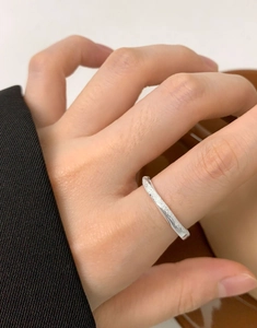 Macro detail of silver Mobius ring with frosted sand finish worn on a finger