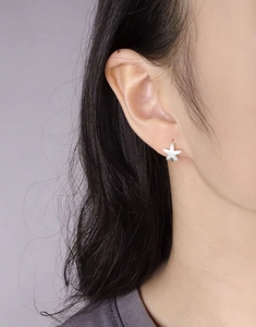 Close-up of a shimmering silver starfish stud earring worn on the earlobe