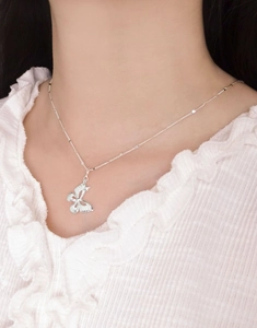 Close-up of minimalist S925 sterling silver butterfly pendant on a delicate chain
