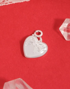Macro shot of silver heart pendant with bow texture on a festive red background