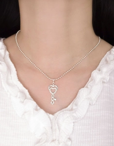 Detailed view of an S925 sterling silver heart-shaped key pendant on a beaded chain