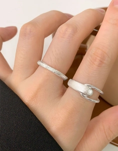 Close-up of matte silver Mobius rings showing brushed texture and hollow design on hand