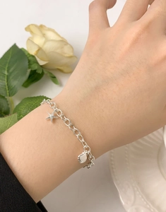 Detailed view of S925 sterling silver starfish and shell charms on a delicate chain bracelet