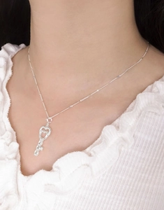 Close-up of S925 sterling silver heart-shaped key pendant necklace on a model