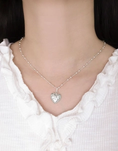 Detail showing an S925 sterling silver heart pendant with a delicate bow on a bead chain