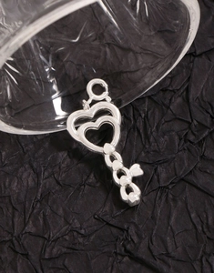 Close-up of S925 sterling silver heart key pendant with detailed engraving on black background