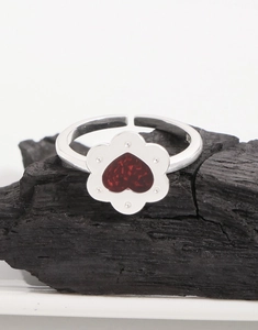 Dettaglio macro dell'anello in argento 925 con fiore e cuore rosso su carboncino