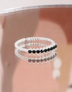 Macro view of twisted S925 silver ring with seven black round stones and mirror reflection