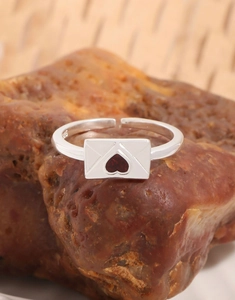 Dettaglio dell'anello a busta in argento S925 con gemma a cuore rosso su pietra grezza