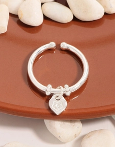Detailed view of S925 silver open bangle with flower engraved heart charm on pebbles