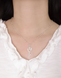 Close-up of a silver hollow heart key pendant necklace worn on a person neckline