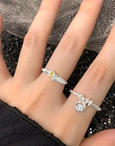 Detail of 925 sterling silver rings with heart charm and yellow gemstone on a hand