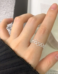 Vue détaillée d'une bague en argent ajourée irrégulière portée par un mannequin en main