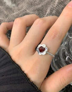 Dettaglio anello in argento S925 con gemma rossa a cuore e petali di fiori