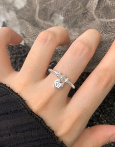 Macro detail of S925 sterling silver ring with a hanging flower heart pendant
