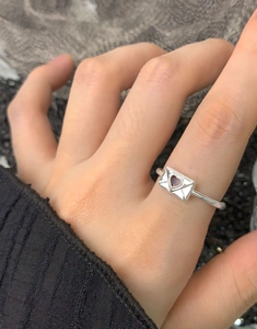 Dettaglio dell'anello a busta in argento S925 con cuore su dito di una donna