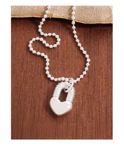 Détail du pendentif cadenas cœur en argent S925 avec chaîne à billes sur fond bois