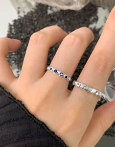 Detail of lava texture silver rings set with deep blue gems on irregular band surface