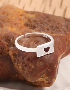 Dettaglio macro dell'anello in argento S925 con forma a busta e cuore rosso centrale