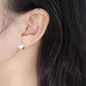 Boucles d'oreilles minimalistes en argent mat portées par un mannequin au style élégant