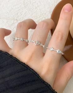 Close-up of S925 sterling silver floral and bow rings worn on a hand in a soft setting