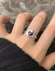 Dettaglio anello in argento S925 con design floreale e gemma rossa a forma di cuore