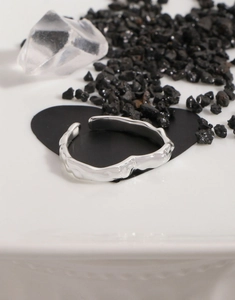 Detailed view of S925 silver lava texture heart open ring on elegant black crystal display