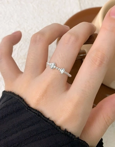 Close-up of S925 silver beaded ring with zircon heart and bow charms on model hand
