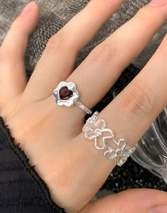 Dettaglio di anelli in argento S925 con design a cuore rosso floreale sulla mano