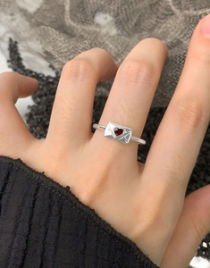 Dettaglio di un anello a busta in argento S925 con cuore in smalto rosso indossato da modella